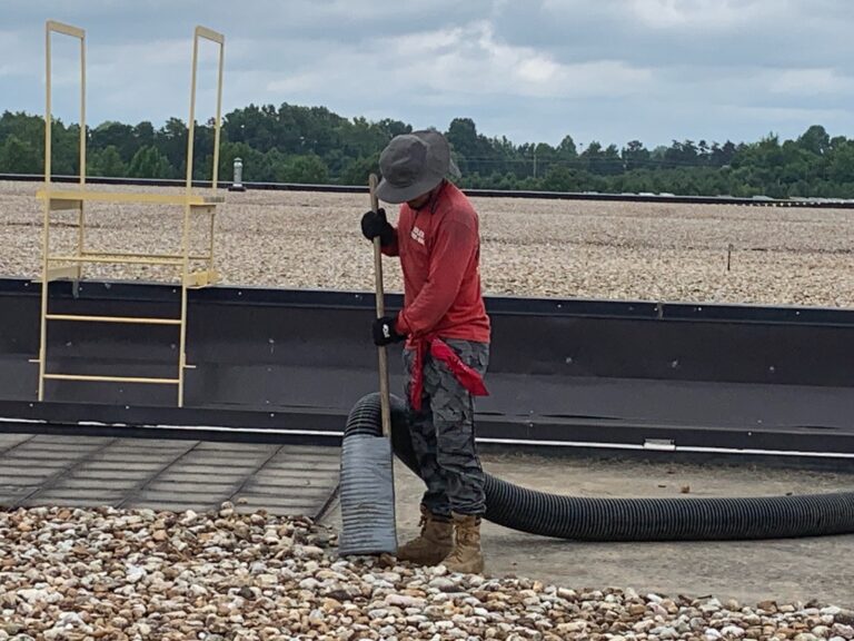 Man removing rocks from industrial roof